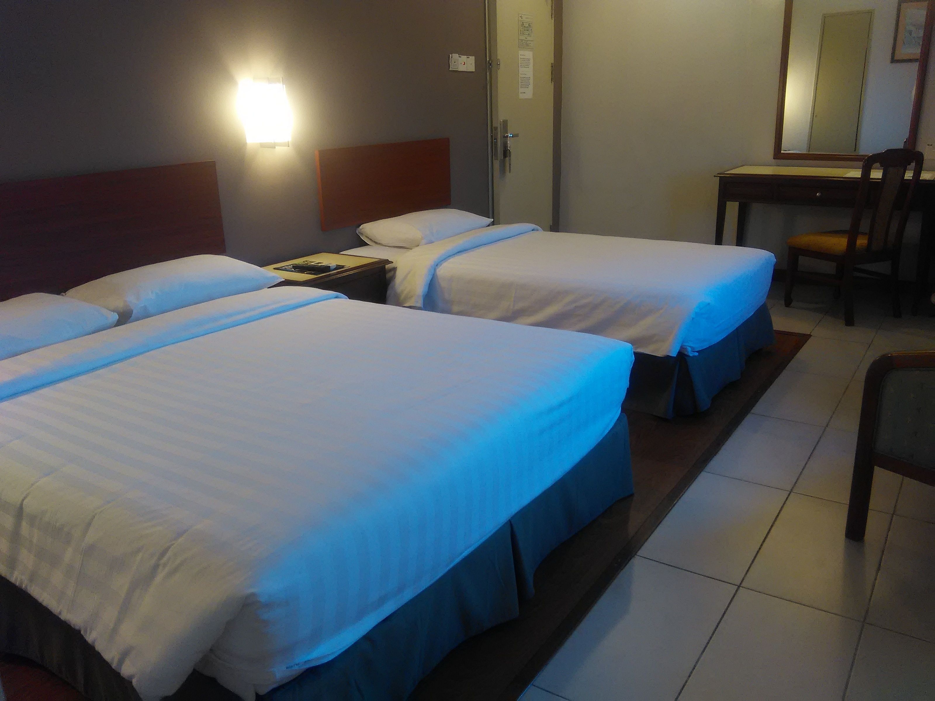 Une chambre d’hôtel avec deux lits, un bureau et une chaise.