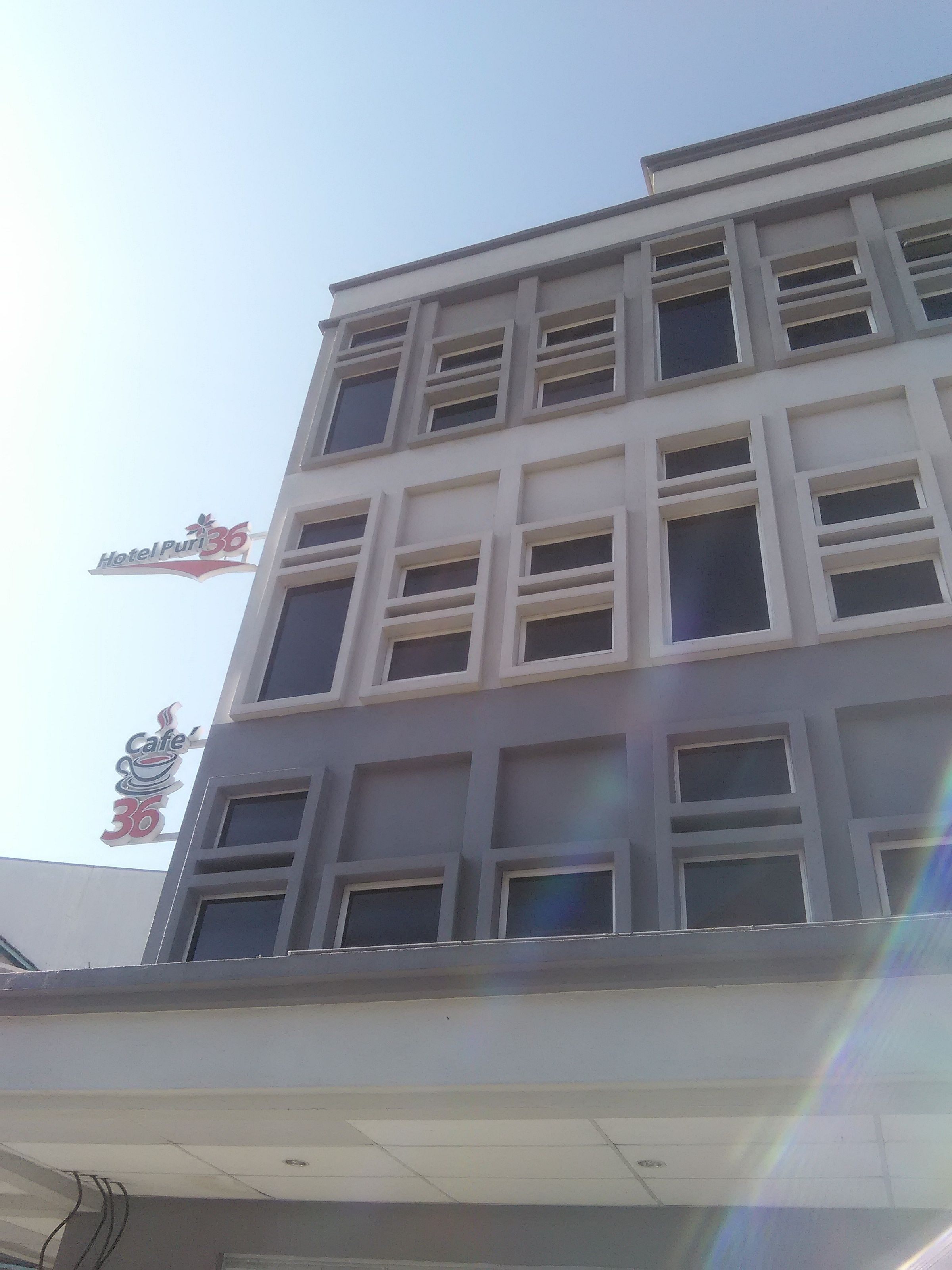 A multi-story building with a sign for Hotel Puri 36 and Cafe 36.
