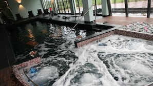 Un jacuzzi con borde de azulejos y una terraza de madera alrededor.