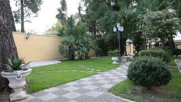 Un patio con un camino a cuadros, plantas en macetas y una pared amarilla.
