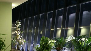 Un pasillo con plantas en macetas y la fachada moderna de un edificio al fondo.