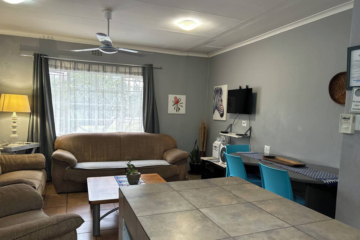 A living room with a sofa, a coffee table, a TV, and a fan.