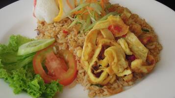 Un plato de arroz frito con verduras y una ensalada al lado.