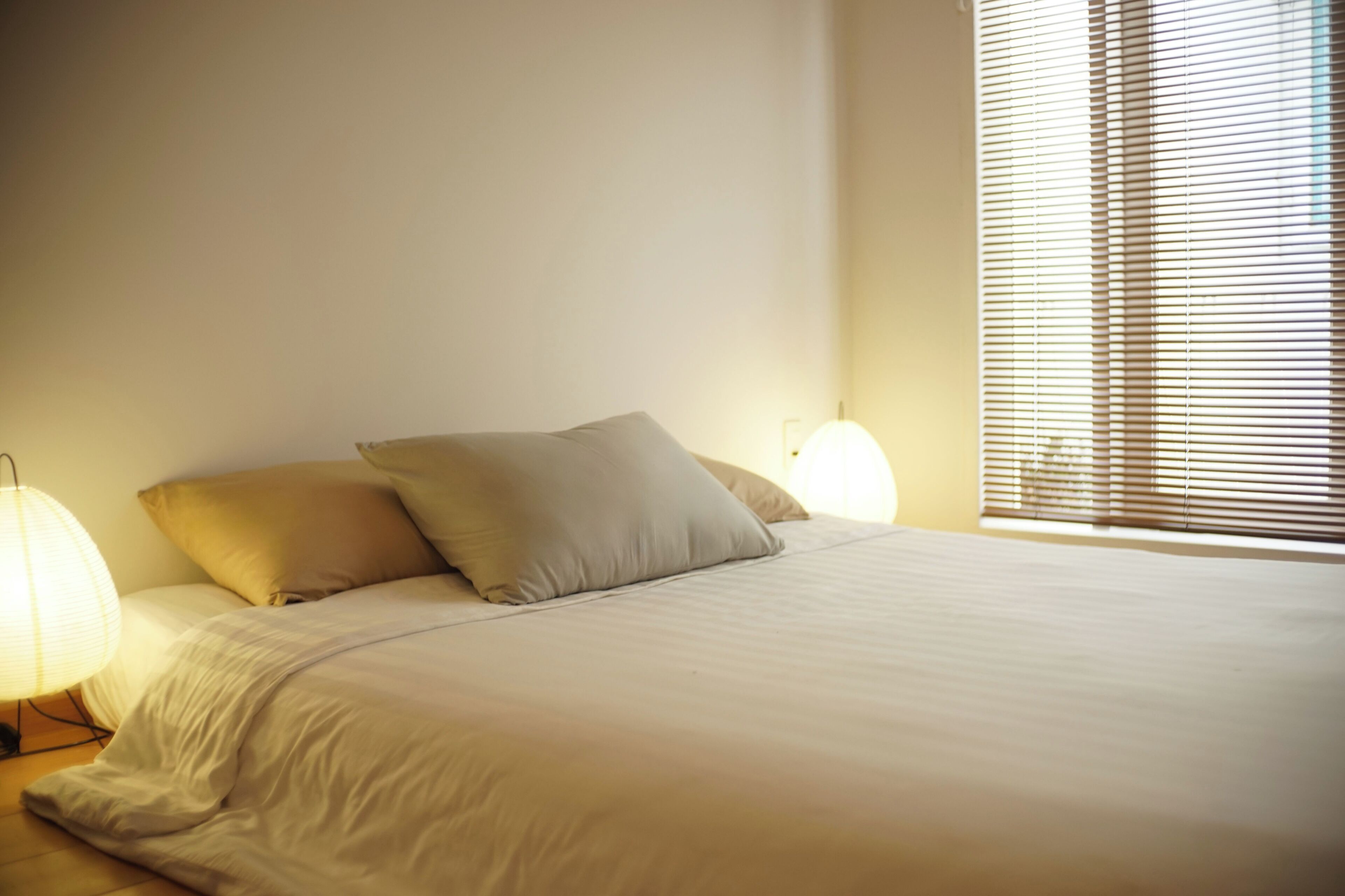 Een net opgemaakt bed met kussens en twee bedlampjes.