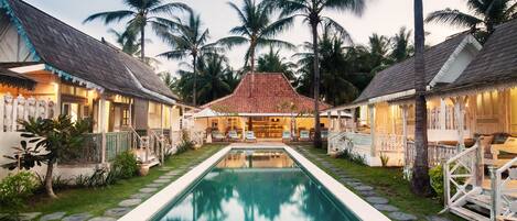 Alberca al aire libre, sombrillas en la alberca y camastros