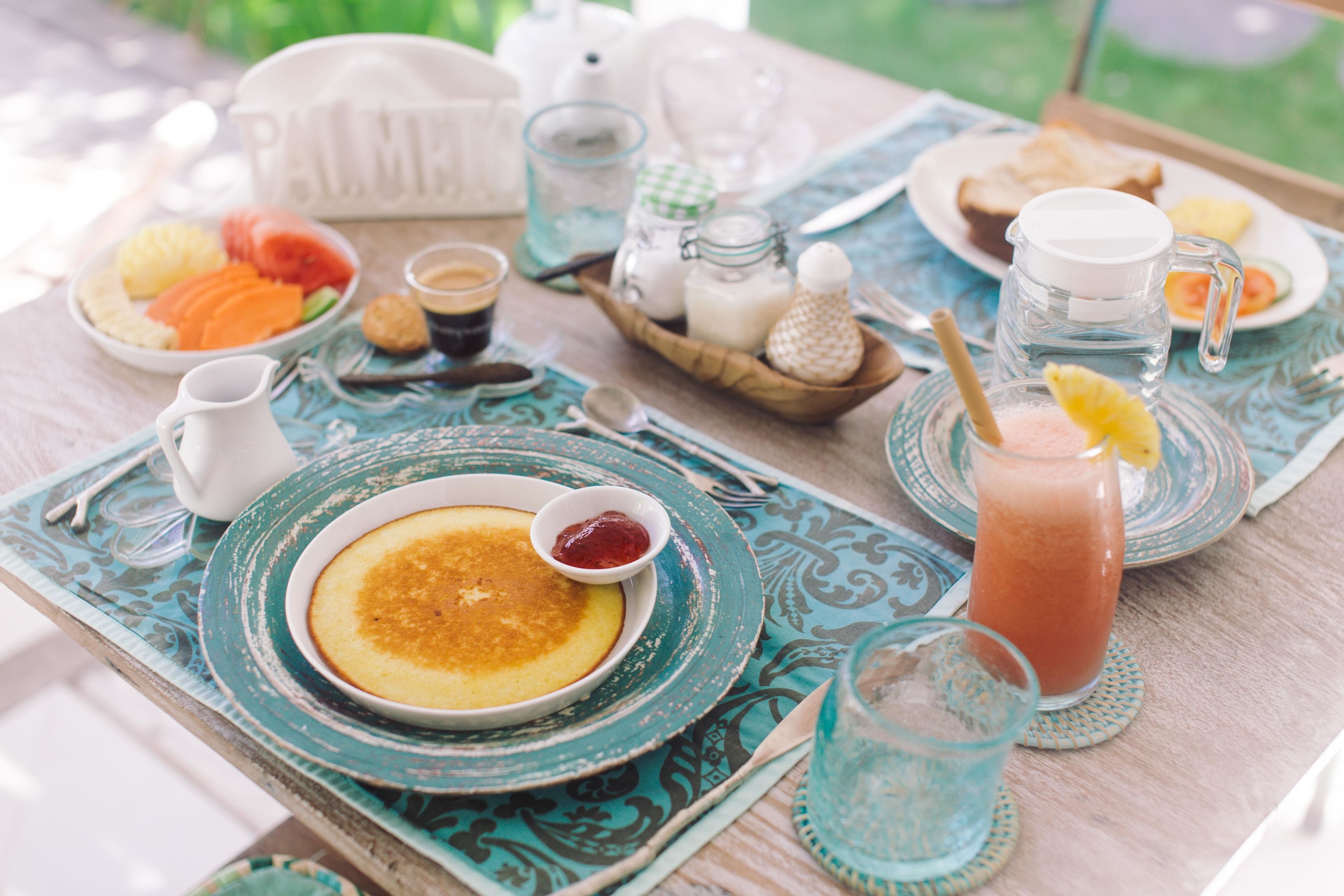 A breakfast table with plates of food, a pitcher, and a glass of juice.