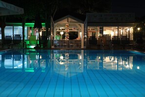 Ein Pool im Freien mit Liegestühlen und einer Snackbar im Hintergrund.