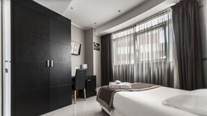 A modern hotel room with a large bed, a desk, and a wardrobe.