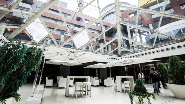 A spacious indoor area with a glass ceiling, modern furniture, and potted plants.