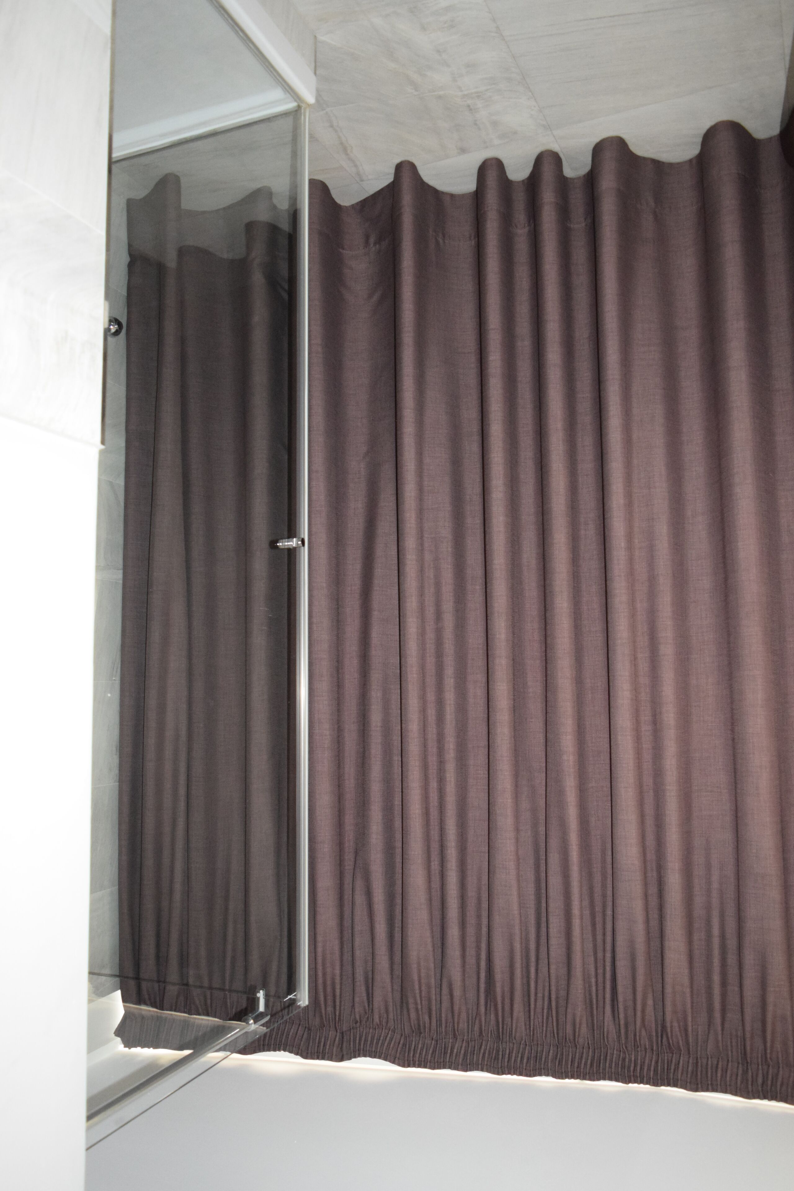 Un baño con ducha, puerta de cristal y cortina.