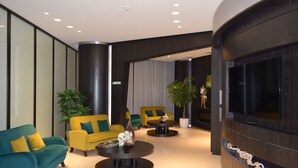 A modern lobby with a sofa, armchairs, a coffee table, and a TV.