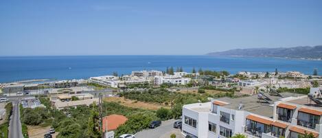 A coastal residential area with modern buildings, a parking lot, and a clear view of the sea.