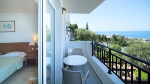 A balcony with a table and chairs, a bed, and a view of the sea. - Semiramis Village (Hersonissos)