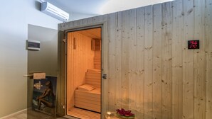 A sauna room with a wooden interior, a digital thermometer, and a small table with candles. - Semiramis Village (Hersonissos)