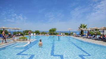 Piscina com água azul cristalina, rodeada por espreguiçadeiras e guarda-sóis, com vista para o mar ao fundo.