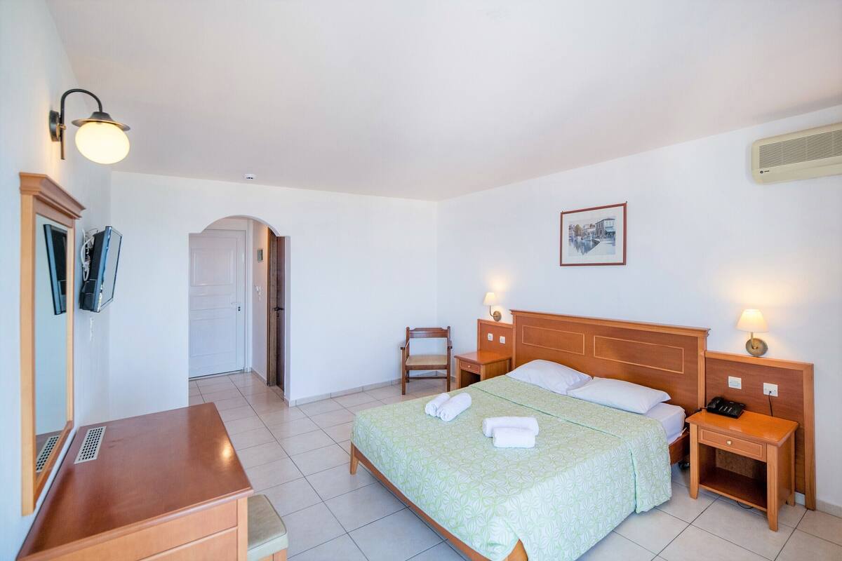 A hotel room with a bed, bedside tables, a desk, and a chair.