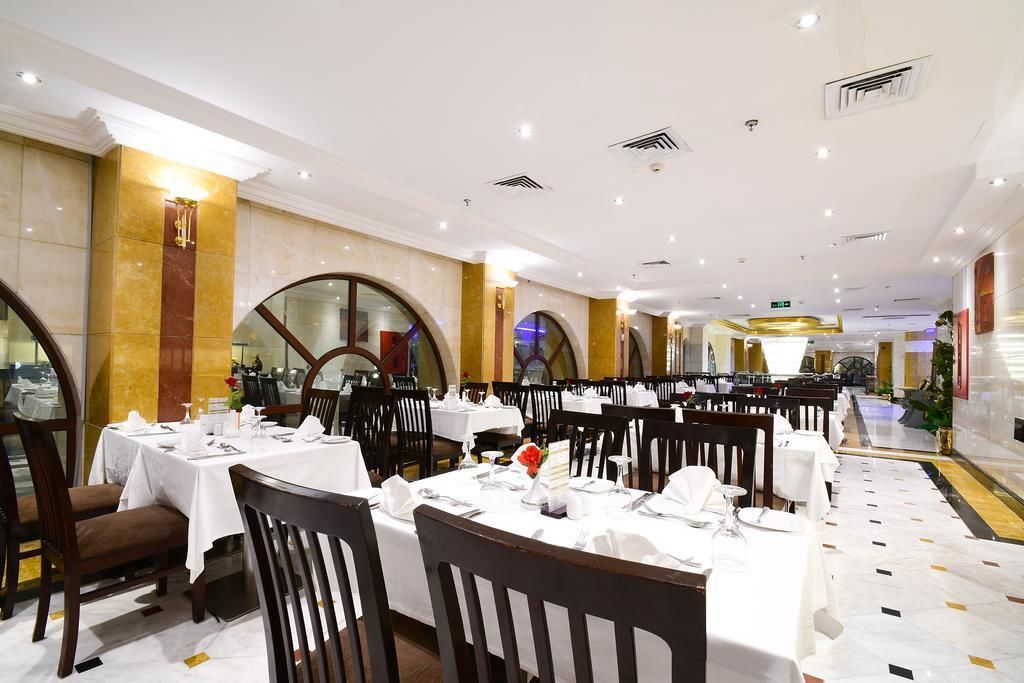 A spacious dining area with multiple tables set for dining, featuring a clean and elegant interior design.