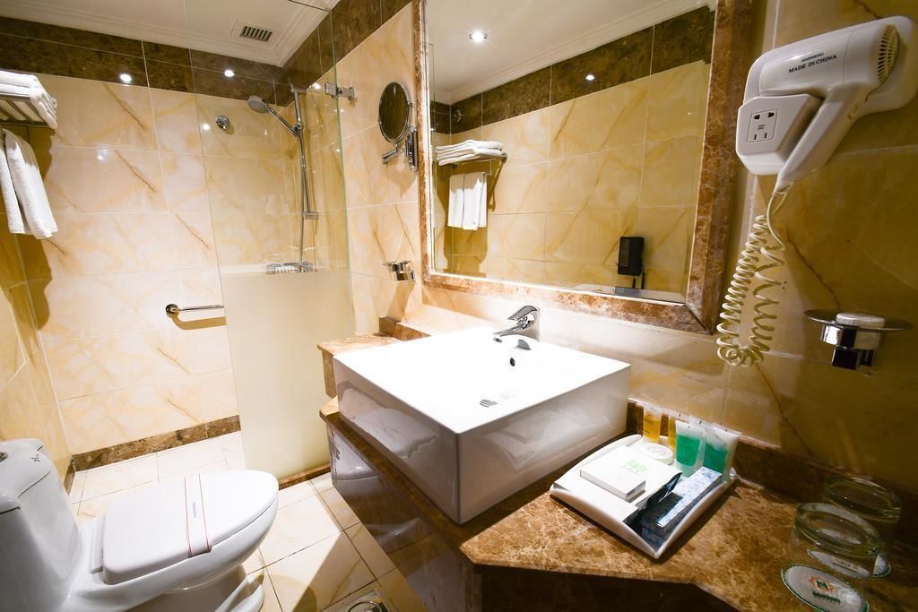 Un bagno con un lavandino ampio, uno specchio, un asciugacapelli e un water.