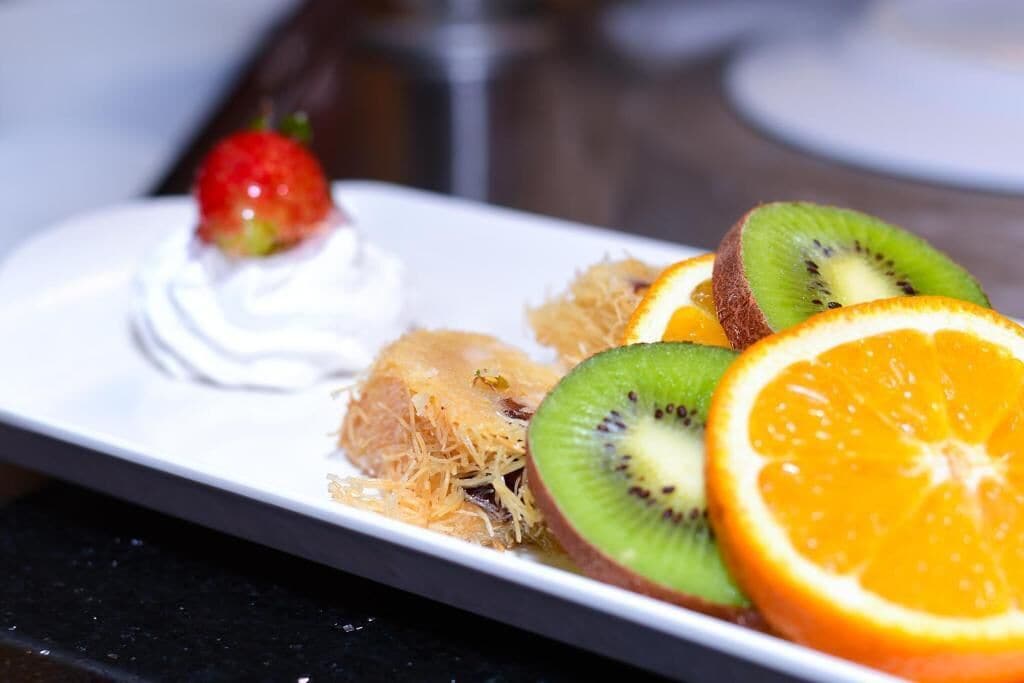 A dessert plate with whipped cream, strawberries, kiwi slices, and orange slices.