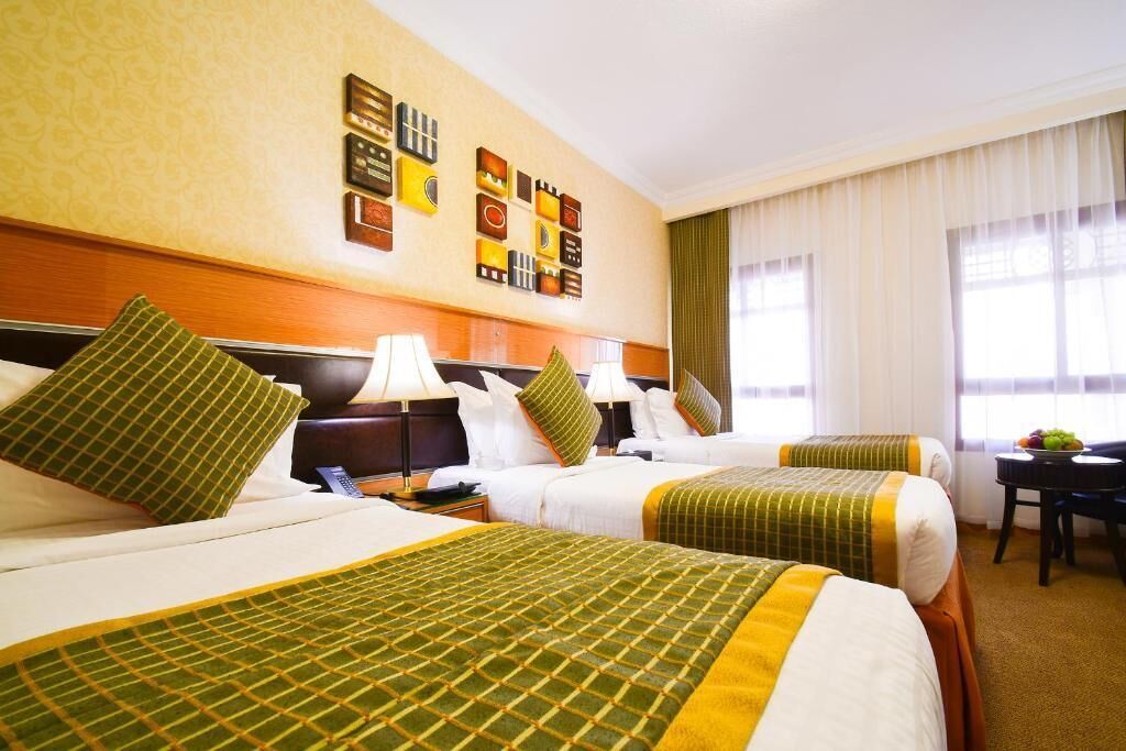 A hotel room with two beds, a desk, and a chair. There are wall decorations and a window with curtains.