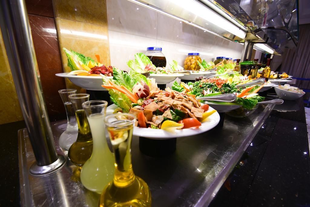 Een buffet met diverse gerechten, waaronder salades, vleeswaren en verschillende soorten sauzen.