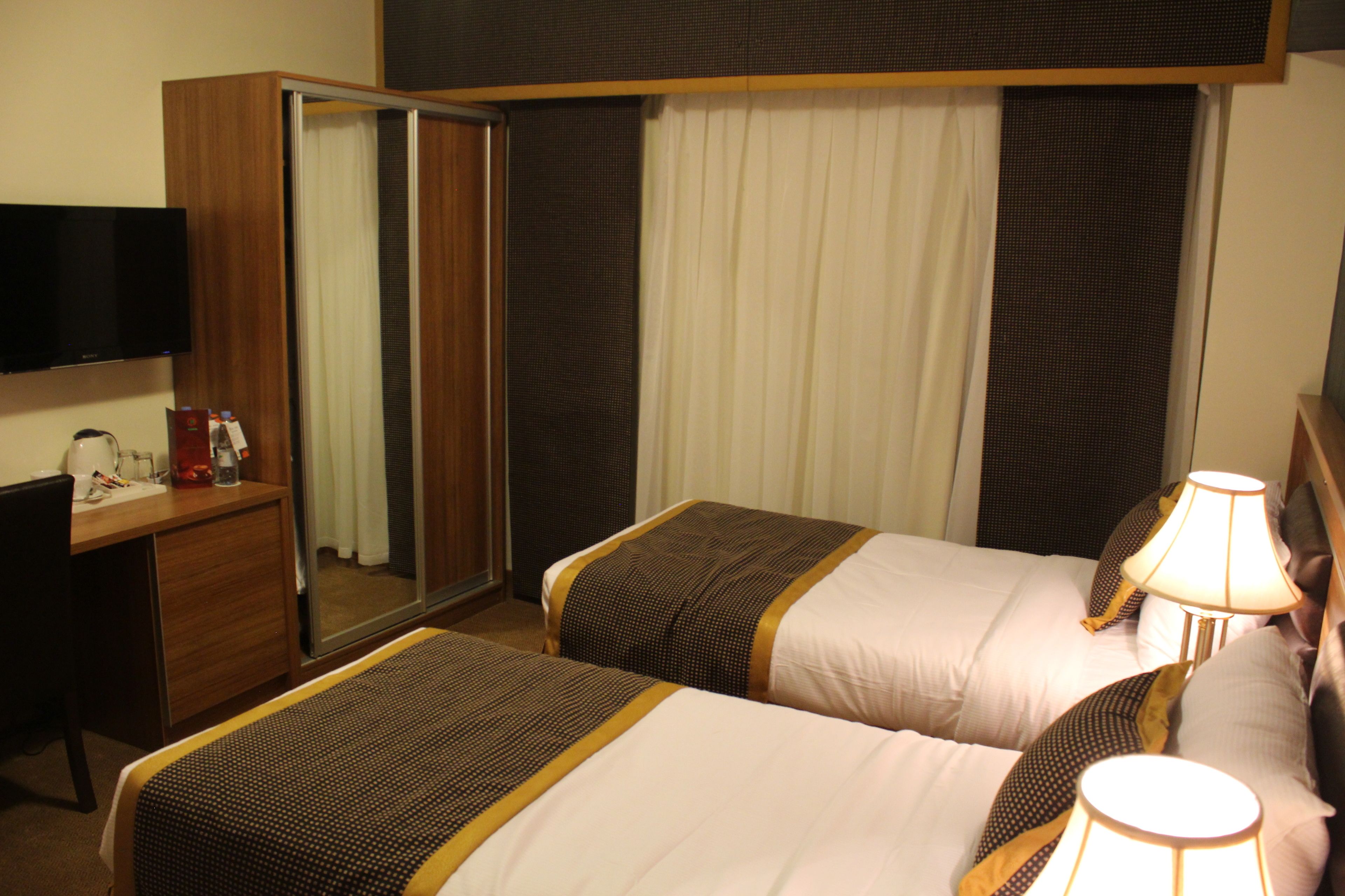 A hotel room with two beds, a TV, a desk, and a wardrobe.