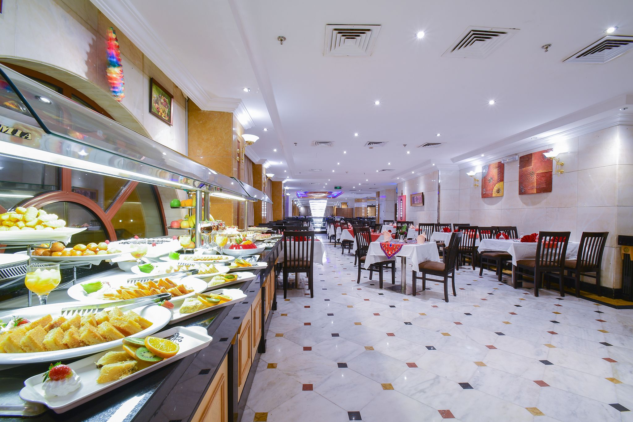 A buffet area with various food items and a long dining table with chairs.