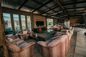 A cozy outdoor living area with a brick fireplace, comfortable seating, and a view of the surrounding landscape. - The Village Lodge (Storms River)