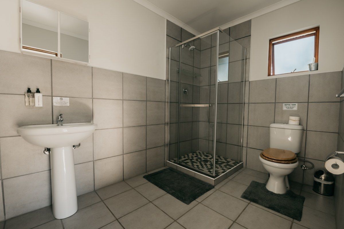 A bathroom with a glass-enclosed shower, a toilet, and a sink.