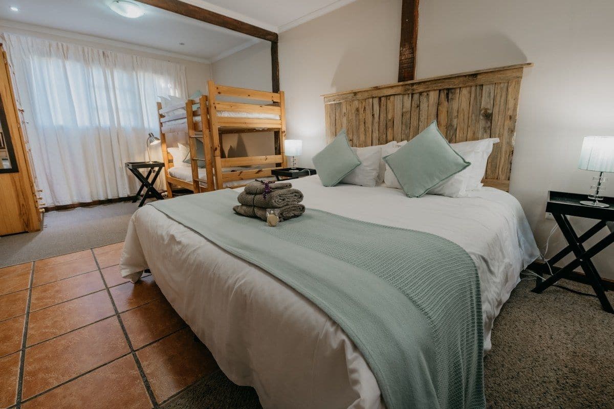 Un dormitorio con una cama grande, cabecero de madera y una cama litera adosada a la pared.