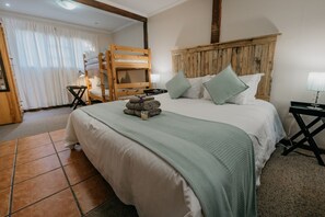 A bedroom with a large bed, wooden headboard, and a bunk bed against the wall.