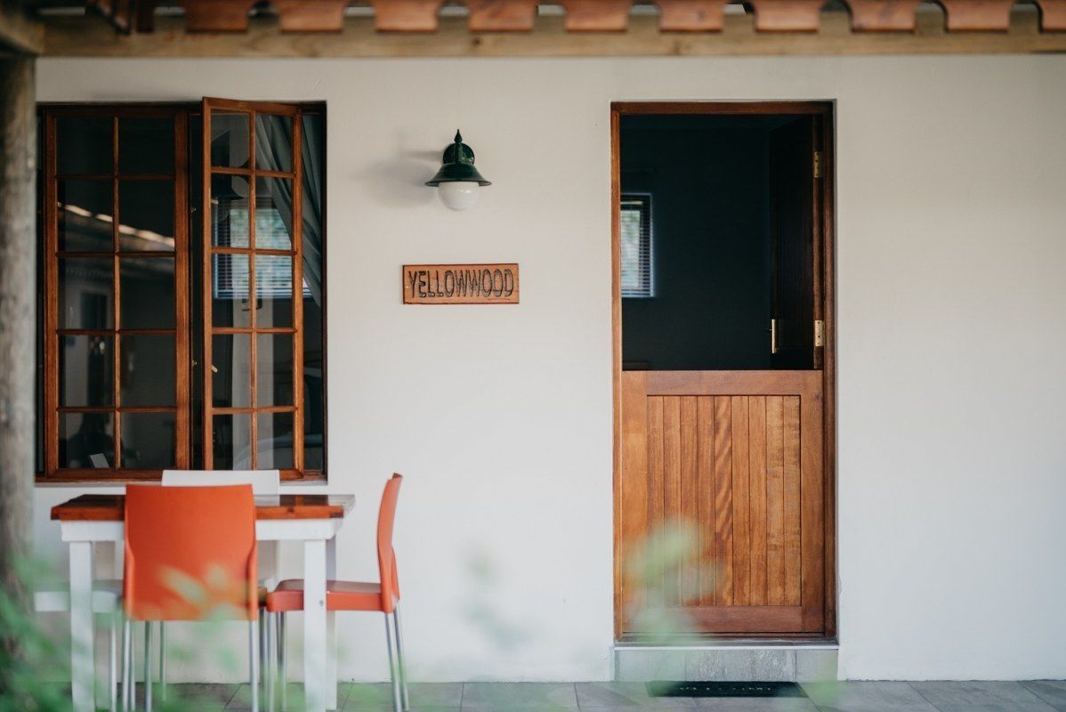 A wooden door with a sign above it, a window with a grid pattern, and a table with two chairs.