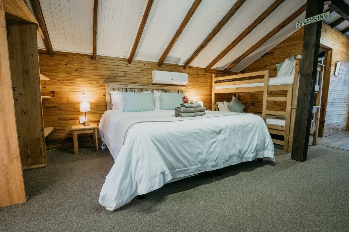 Acogedora habitación tipo cabaña de madera con literas, una mesita de noche con lámpara y un cartel que indica prohibido fumar.