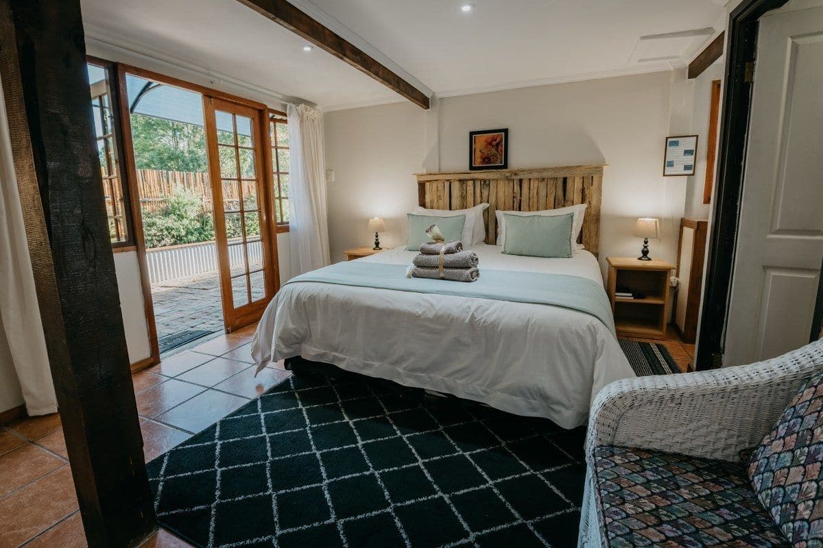 Un dormitorio con una cama grande, dos mesitas de noche, una silla y vistas al exterior.