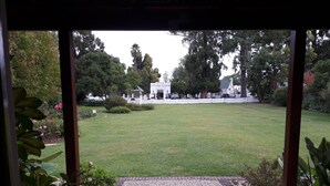 A view of a well-maintained lawn and a white fence surrounding a property. - The Village Lodge (Storms River)