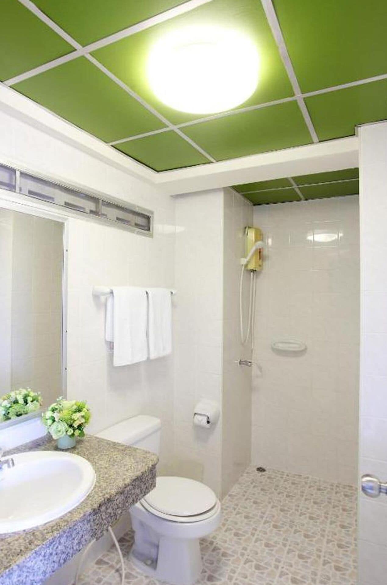 A bathroom with a green ceiling, white tiles, a sink, a toilet, and a shower.