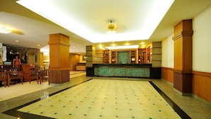 A spacious lobby with a high ceiling, a reception desk, and a seating area with wooden chairs. - Rambuttri Village Inn & Plaza (Bangkok)
