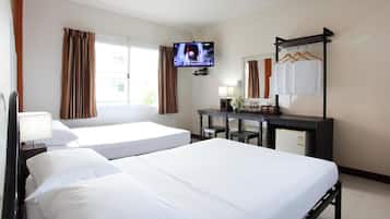 A hotel room with two single beds, a TV, a desk with a mirror, and a wardrobe with hanging clothes.