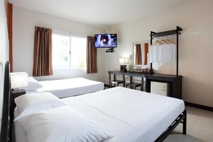 A hotel room with two single beds, a TV, a desk with a mirror, and a wardrobe with hanging clothes.