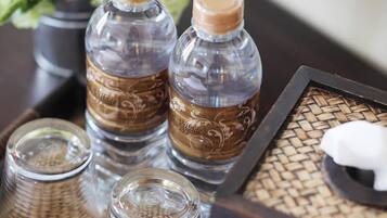 A tray with two bottles and three glasses on a woven mat.