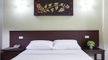Habitación de hotel con una cama grande, dos mesitas de noche, una obra de arte en la pared y una mesita con un teléfono.