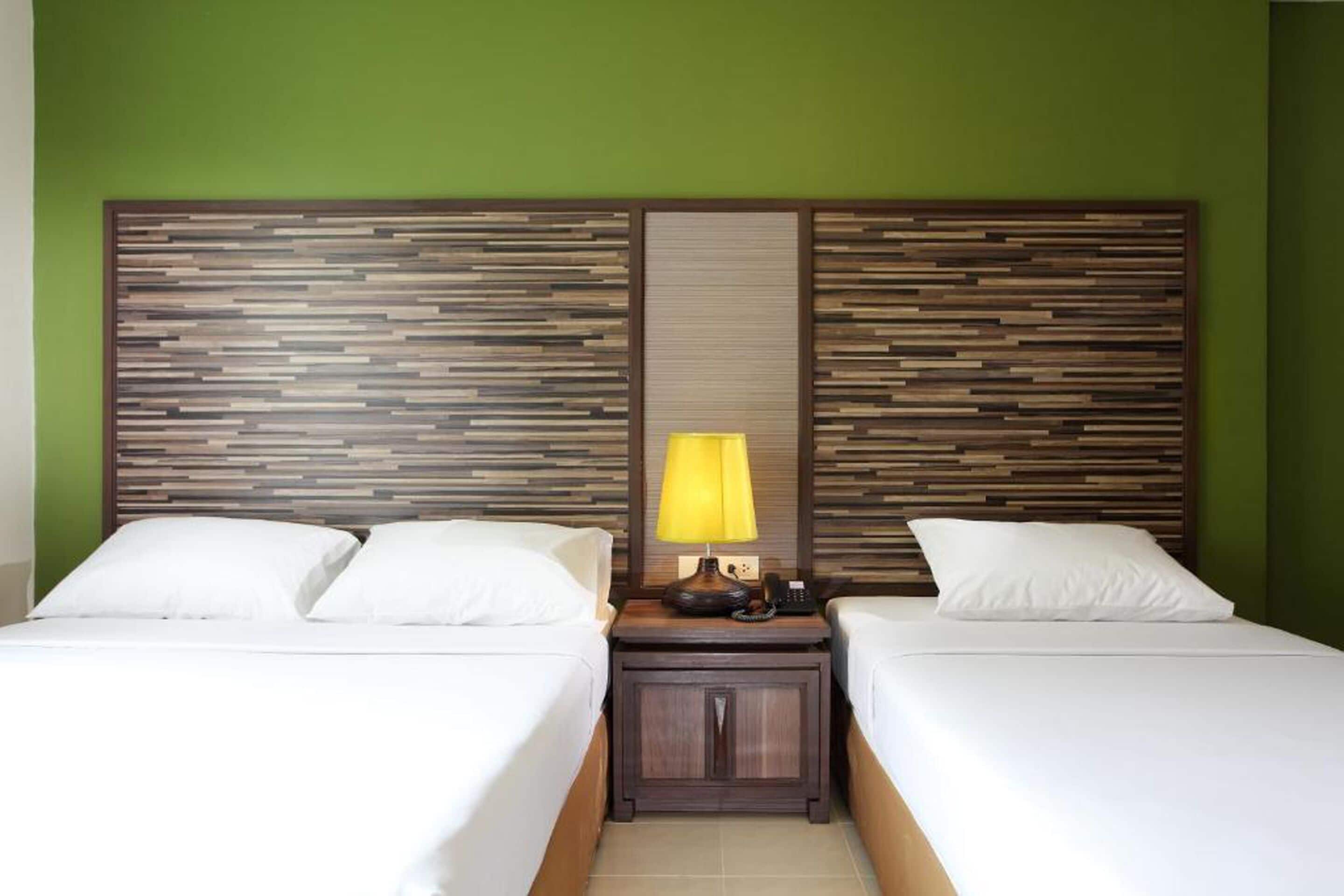 Ein Hotelzimmer mit zwei Betten, einem Holzkopfende, einem Nachttisch mit Lampe und einem Telefon.