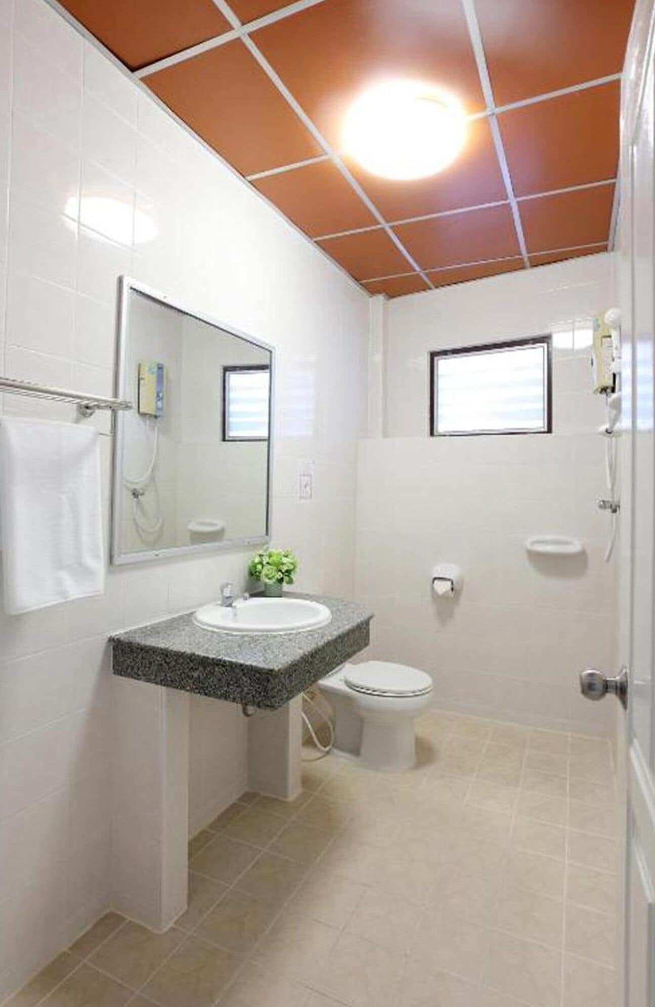 Un baño con lavamanos, espejo e inodoro blancos.