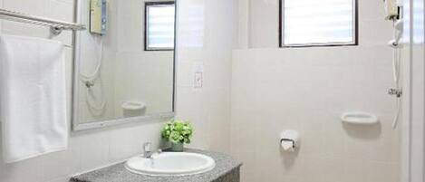 Un baño con lavamanos, espejo e inodoro blancos.