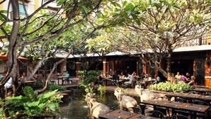 An outdoor dining area with tables and chairs, surrounded by lush greenery and a small water feature. - Rambuttri Village Inn & Plaza (Bangkok)