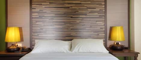 A hotel room with a bed, two bedside lamps, and a wooden headboard.