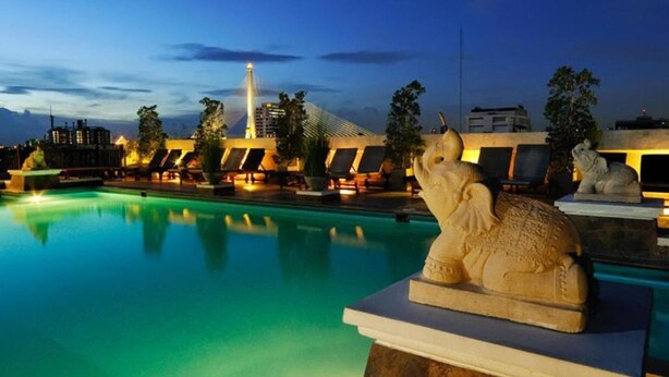 A pool area with a statue of an elephant, lounge chairs, and a building in the background. - Rambuttri Village Inn & Plaza (Bangkok)