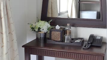 Une console en bois, avec un miroir au-dessus, un petit tabouret devant, et un vase rempli de fleurs.