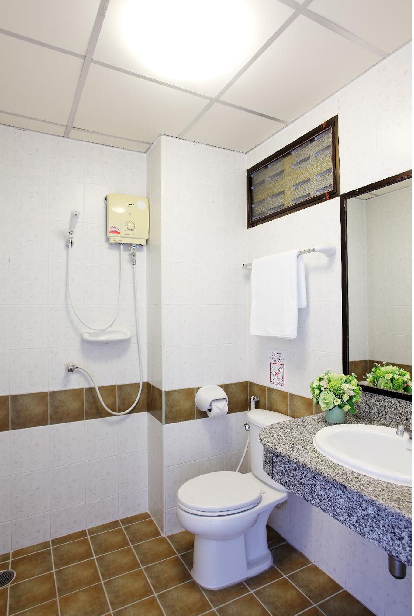 A bathroom with a toilet, sink, shower, and a towel rack.
