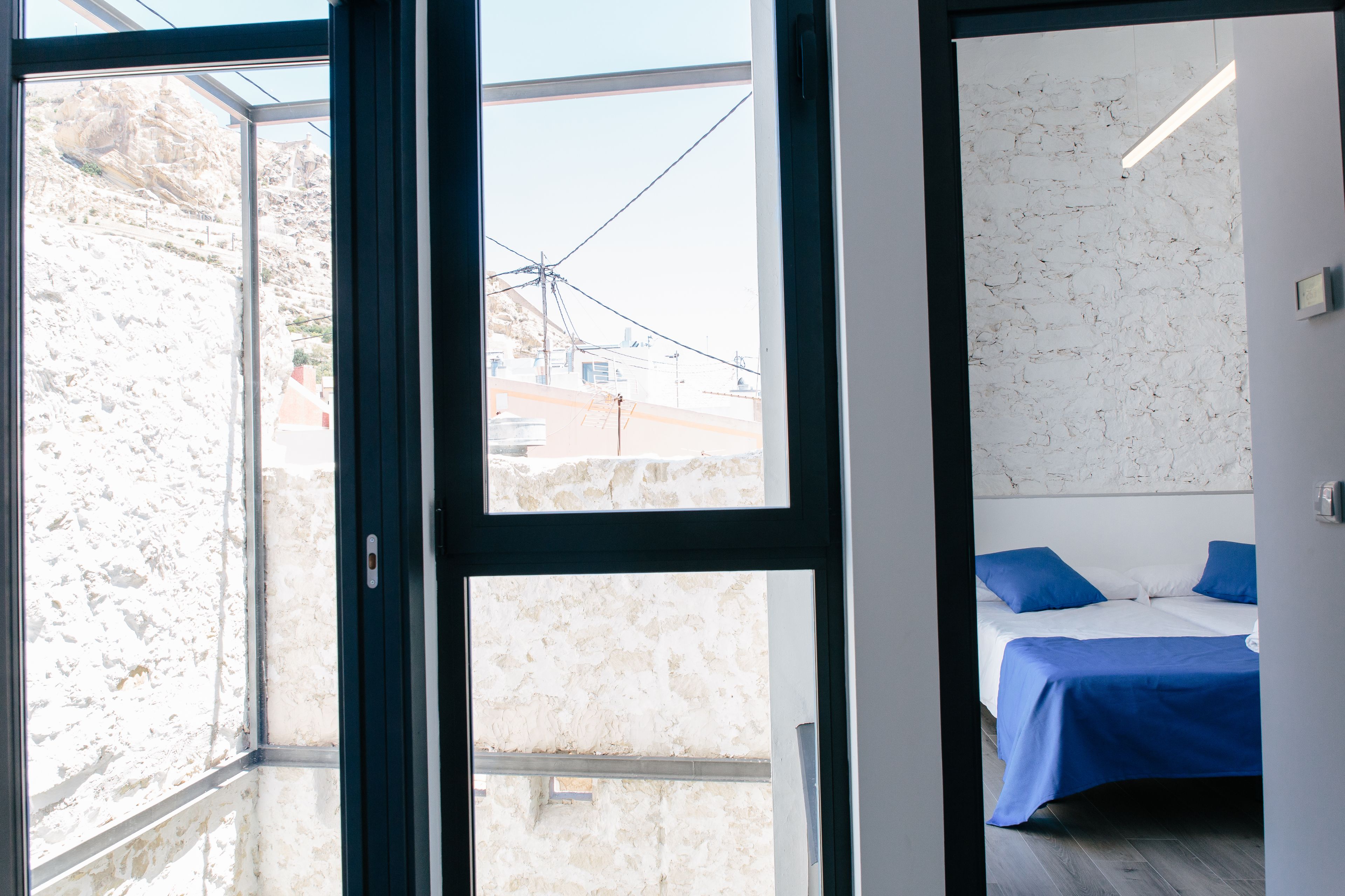 A modern room with a bed, a window, and a view of a rocky landscape.
